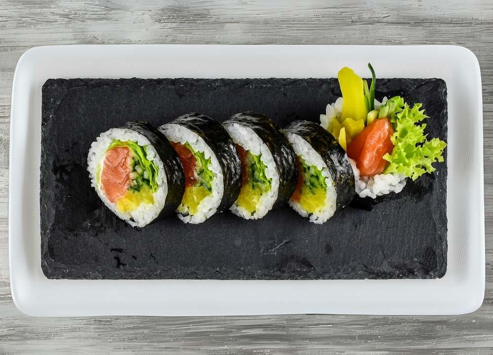 عدة رولات سوشي ماكيزوشي مقطعة تحتوي على سلمون وأرز وخضروات