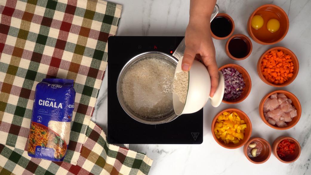 Riz Cigala versé dans une casserole d'eau bouillante pour la cuisson, première étape de la recette de riz frit indonésien.
