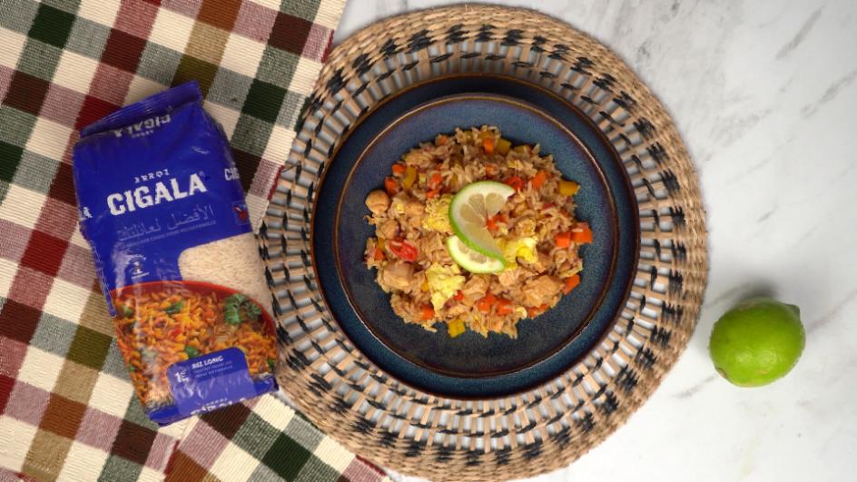 Plat de Nasi goreng indonésien avec riz, poulet, légumes et œuf brouillé, garni d'une tranche de citron vert, prêt à déguster.