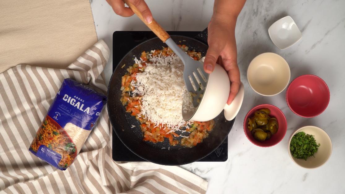 Incorporation du riz Cigala cuit au mélange de tomates et oignons pour préparer le riz à la mexicaine.