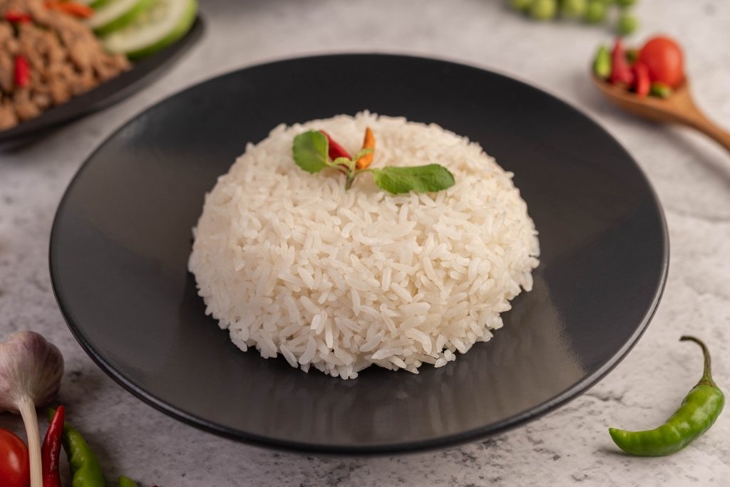 طبق من الأرز الأبيض المطبوخ يُقدَّم على صحن أسود مزين بقطعة فلفل حار وأوراق نعناع.