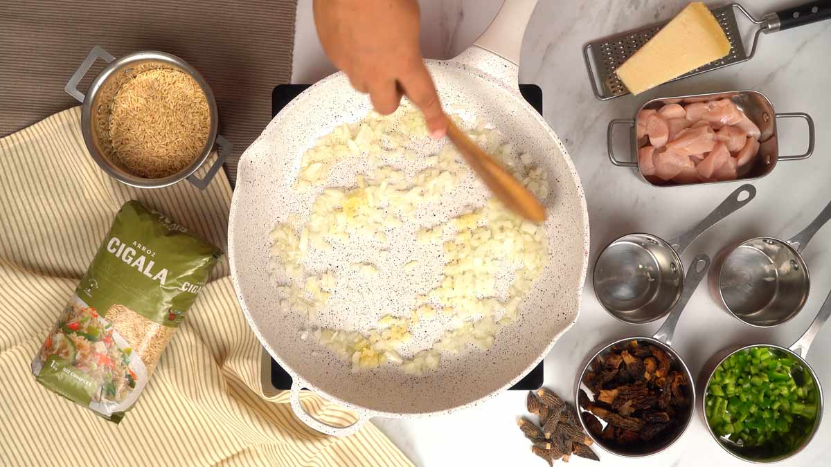 تشويح البصل والثوم في زيت الزيتون لتحضير وصفة الأرز بالدجاج والفطر