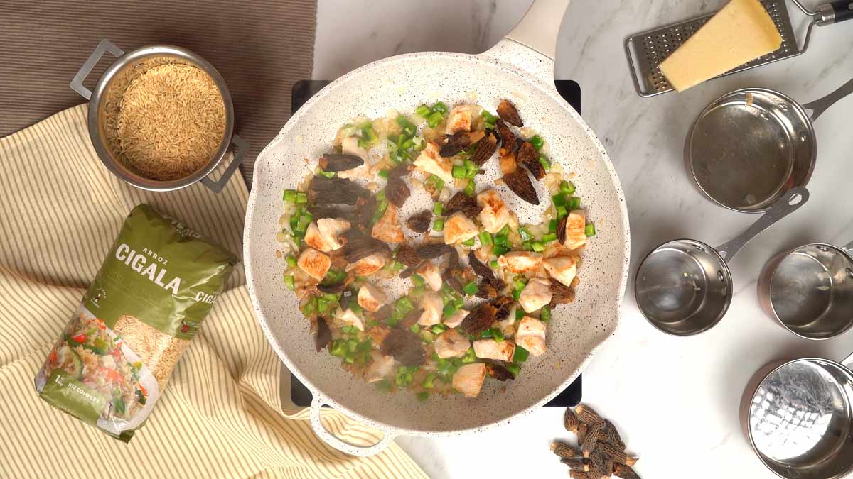 في مقلاة بيضاء، الخضار والدجاج والفطر يطهى بجانب الأرز الكامل Arroz Cigala