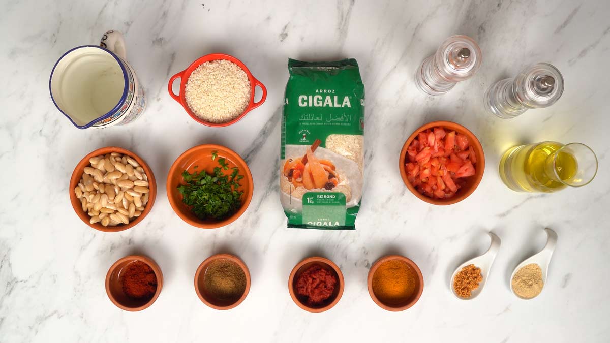 Préparation des ingrédients Tous les ingrédients nécessaires à la recette sont disposés sur la table, avec le riz, les haricots blancs et les épices.