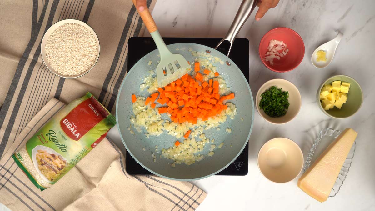 Ajouter la citrouille Une personne ajoute des dés de citrouille aux oignons et les fait revenir dans la poêle.