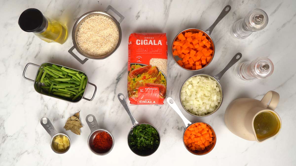 تحضير المكونات جميع مكونات الوصفة، بما في ذلك الأرز، والخضروات المقطعة، والمرق، موضوعة على الطاولة.
