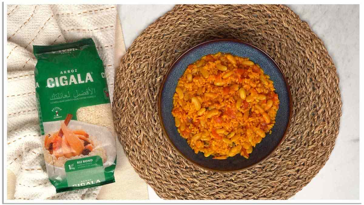 Finition et service Un plat de riz aux haricots blancs et à la sauce tomate est servi dans un bol bleu foncé.