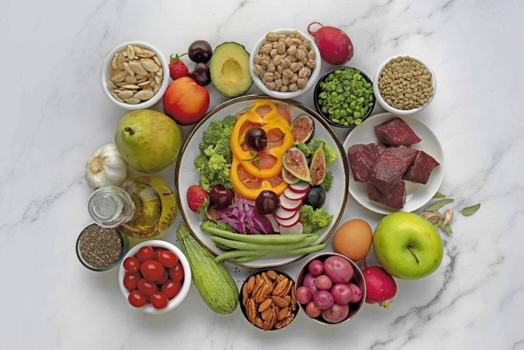 Un compromis entre végétarisme et liberté Vue d'en haut d'une composition d'aliments sains (légumes, fruits, noix et légumineuses) autour d'une salade sur une surface en marbre.