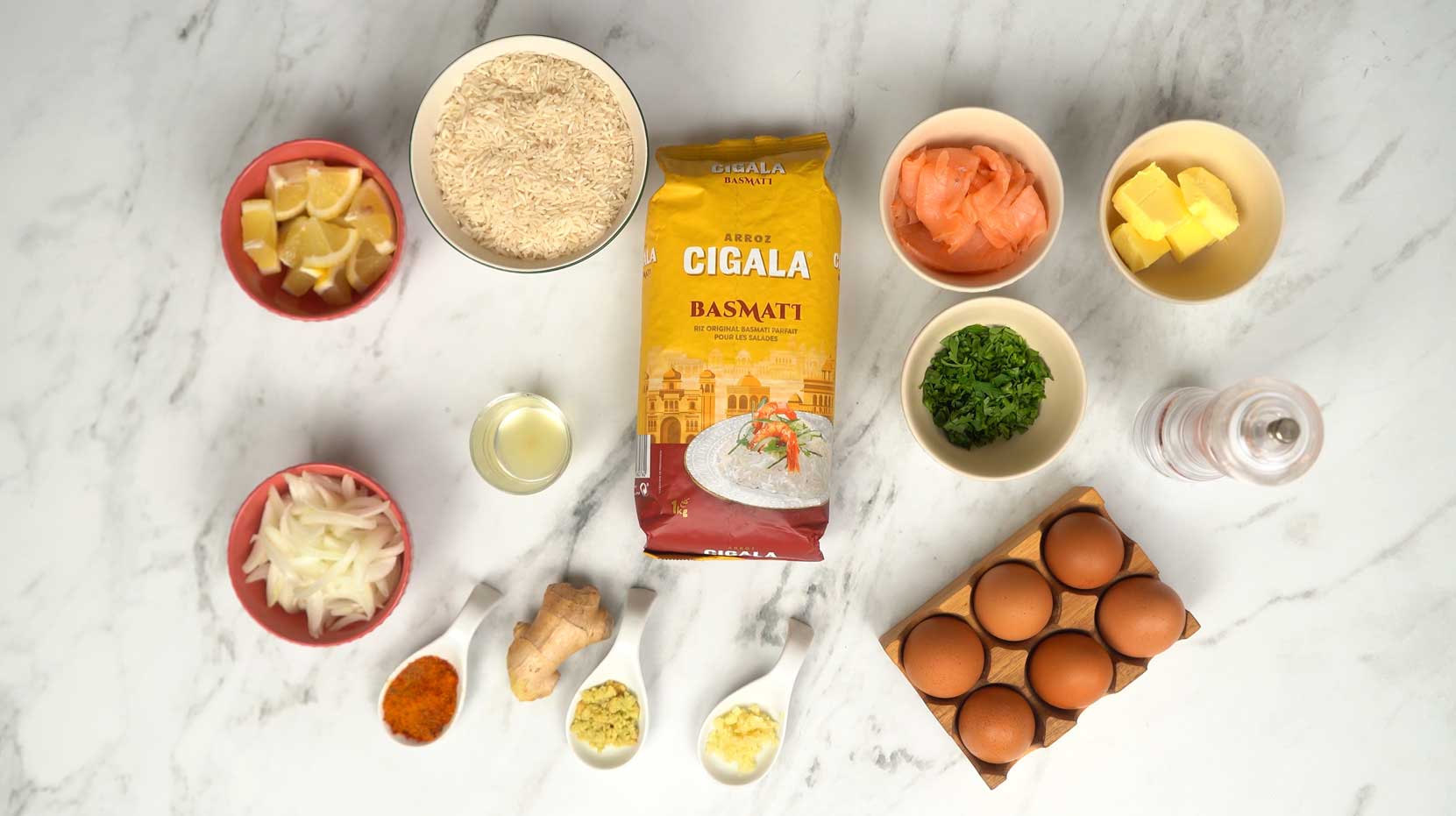 يتم جمع المكونات الأساسية، بما في ذلك أرز البسمتي، والسلمون المدخن، والبيض، والزبدة، والتوابل مثل الغارام ماسالا.