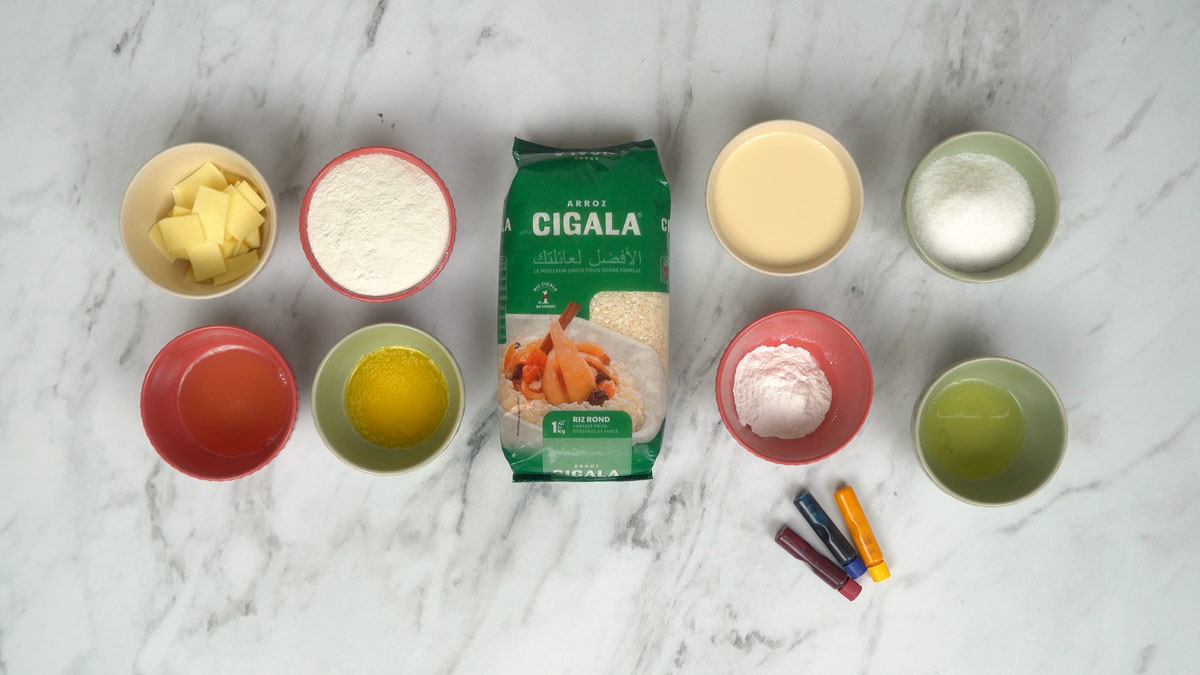 نحضّر المكوّنات الأساسية، بما في ذلك أرز سيكالا المستدير، والسكر، والحليب، والزبدة، إضافة إلى ملوّنات غذائية باللونين الأزرق والأحمر والأصفر.