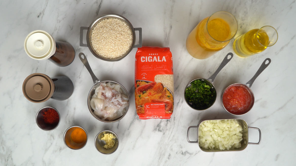 نحضّر المكوّنات اللازمة، بما في ذلك حلقات الكاليمار، وأرز سيكالا المتوسط، والبصل المفروم، وصلصة الطماطم، ومزيج من التوابل.