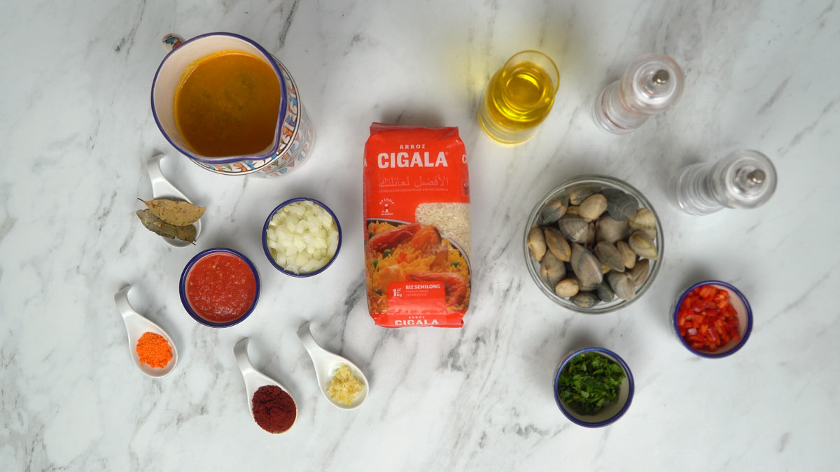 نحضّر المكوّنات، بما في ذلك محار طازج، وأرز، ومرق، وصلصة طماطم، وتوابل، وبصل مفروم.