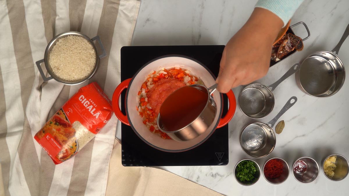 نبدأ بتشويح البصل والفلفل في قدر قبل إضافة صلصة الطماطم والمرق.