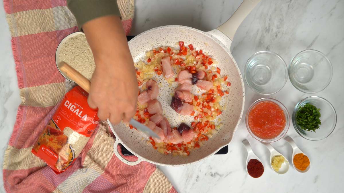 Préparation de la base aromatique On commence par faire revenir les morceaux de poisson avec des oignons et des poivrons émincés dans une poêle avec un filet d'huile.