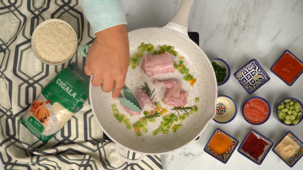 Les morceaux de lapin sont mis à dorer dans une sauteuse avec de l'huile d'olive, du poivron vert et des herbes aromatiques comme le romarin ou le thym.