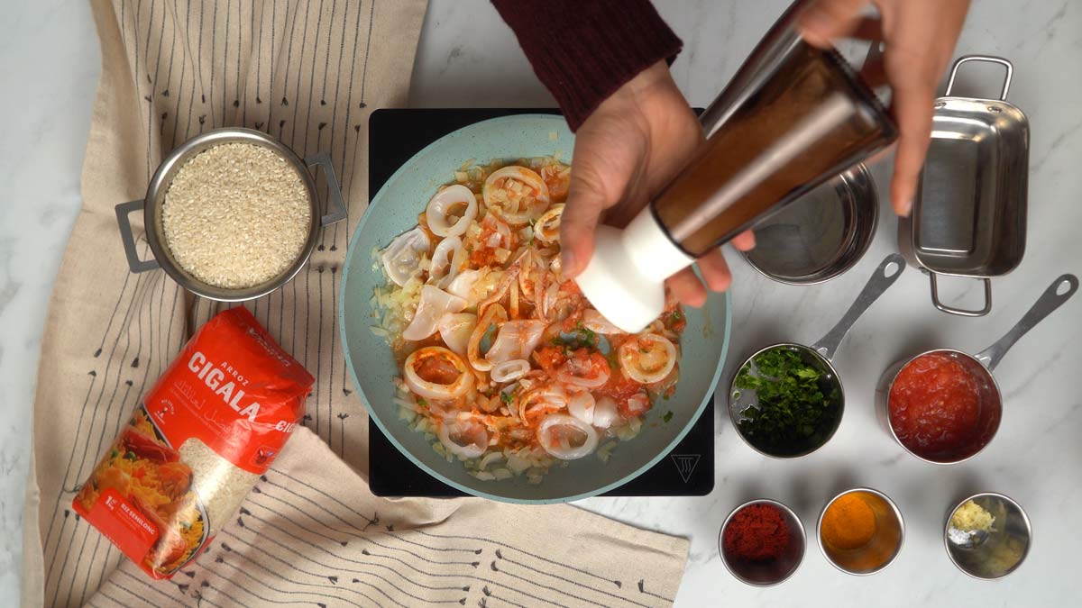 نضيف الكاليمار وصلصة الطماطم إلى البصل، ثم نُتبّل الخليط بالملح والفلفل.