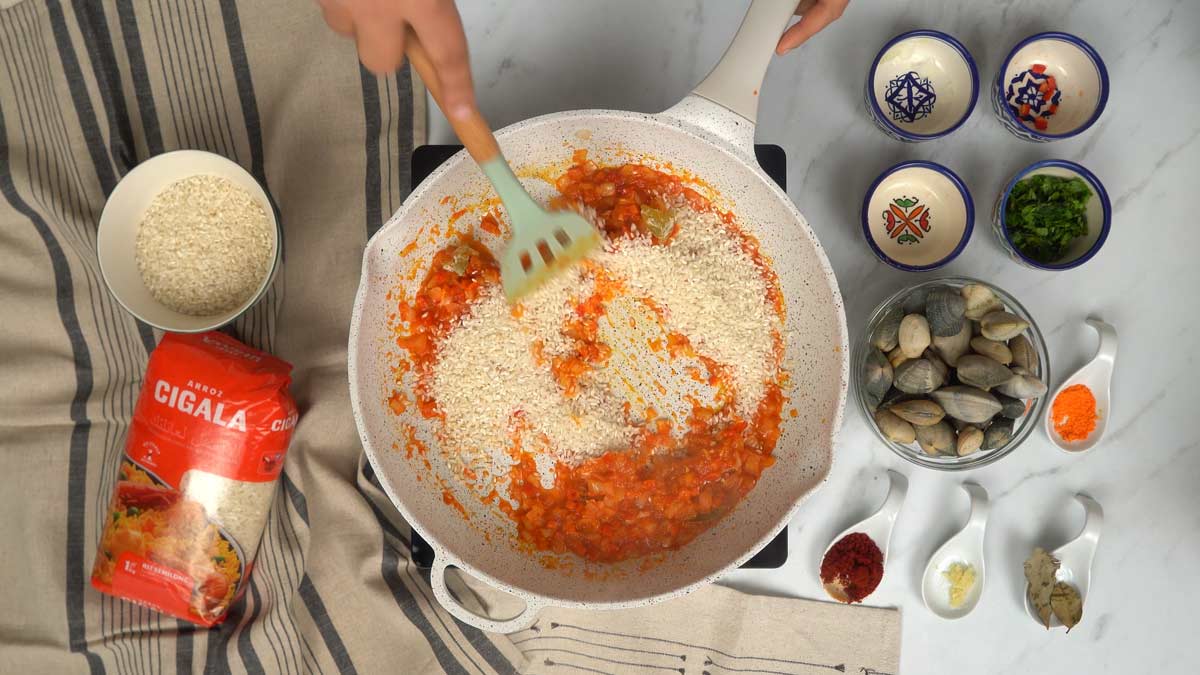 نضيف الأرز النيّئ إلى القاعدة العطرية ونحرّك ليَتشرّب النكهات.