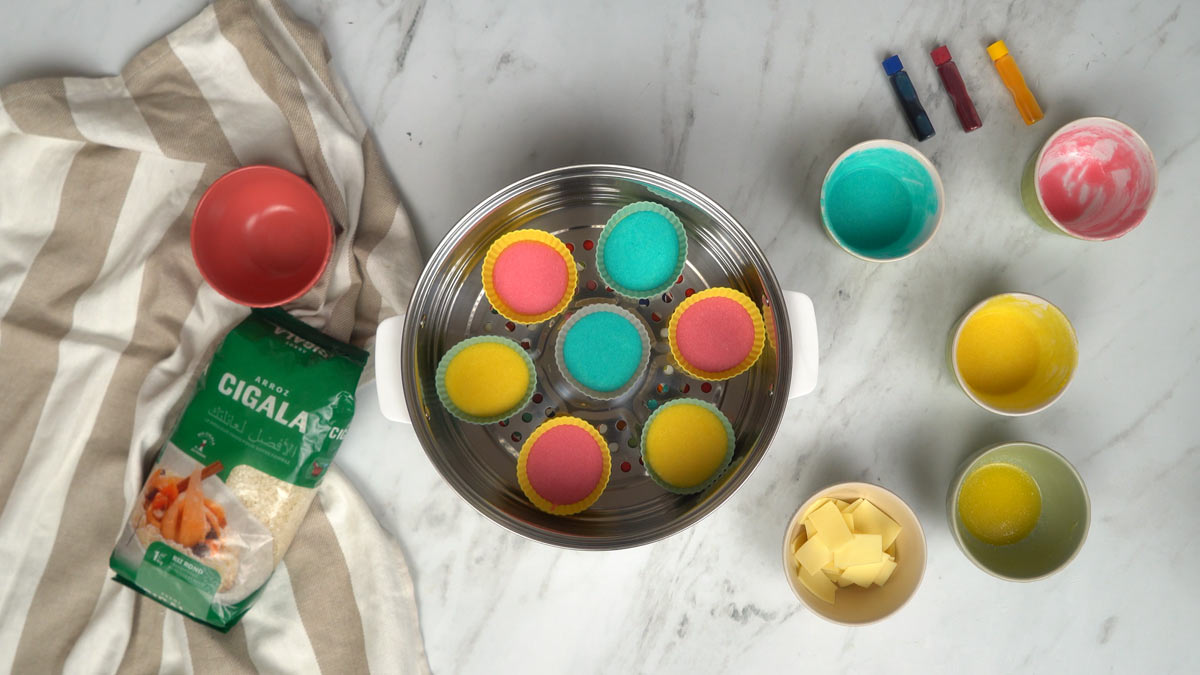 نضع القوالب الصغيرة المملوءة بالخليط الملوّن في جهاز الطهي على البخار حتى تنضج.