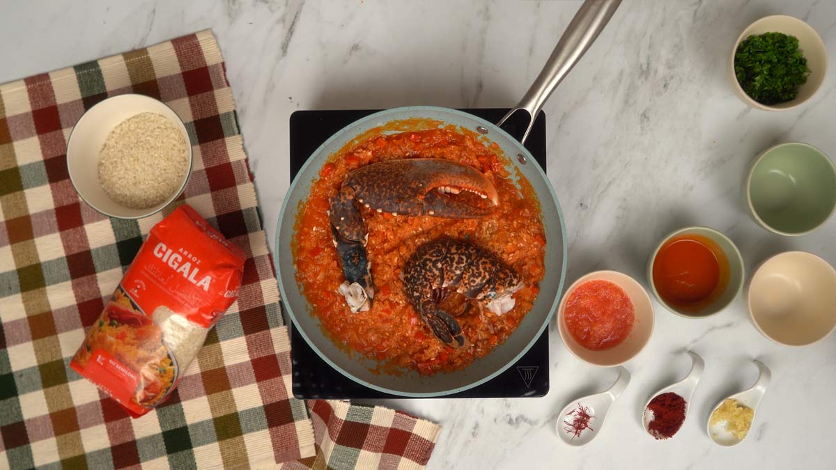 إضافة الكركند تُضاف قطع الكركند إلى المزيج ويُسكب المرق لإتمام طهي الأرز.