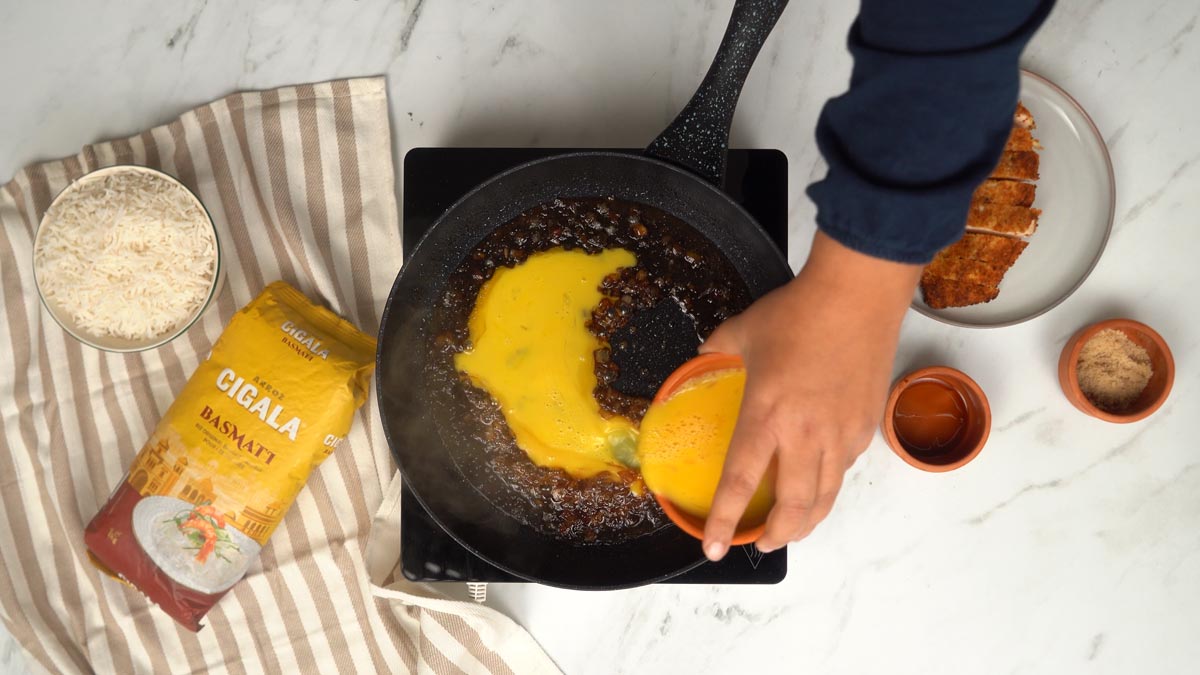 يُسكب البيض المخفوق فوق خليط البصل لتكوين طبقة ناعمة تربط النكهات.