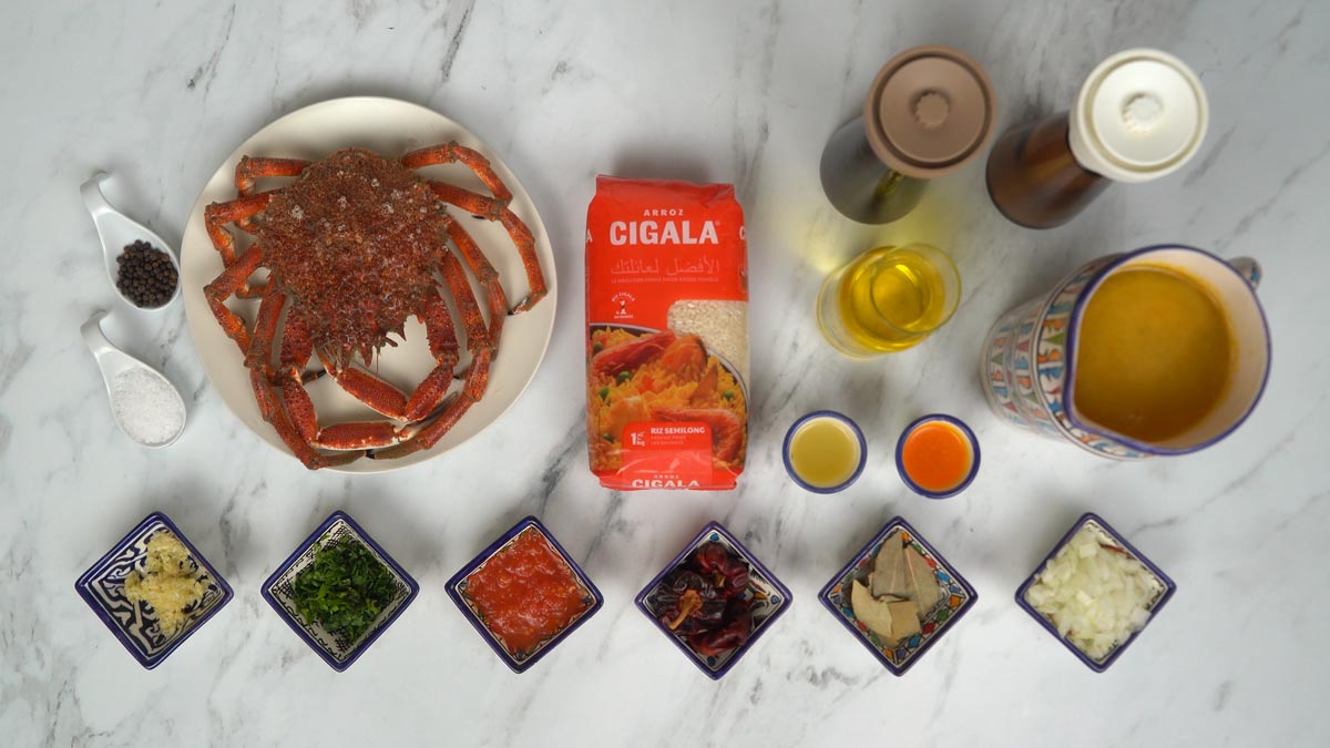 نحضّر المكوّنات، بما في ذلك سلطعون كامل، وأرز، ومرق، وصلصة طماطم، إضافة إلى توابل وأعشاب طازجة.