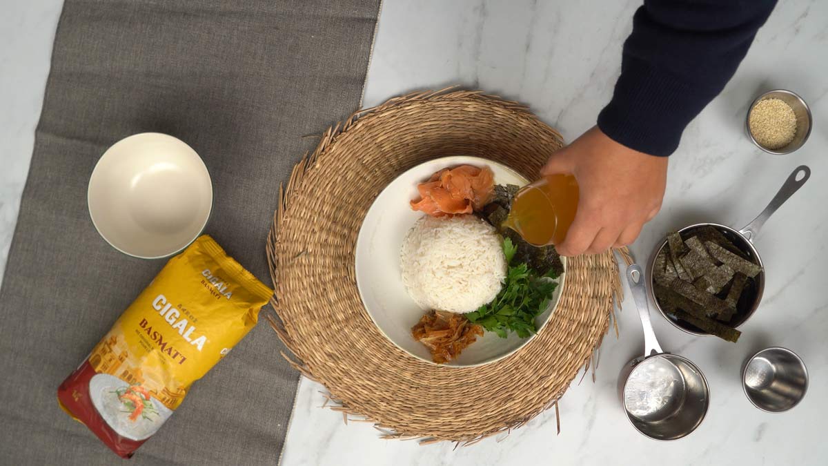 On dispose une portion de riz au centre d'un bol, on place les garnitures tout autour, puis on verse délicatement le bouillon chaud par-dessus.