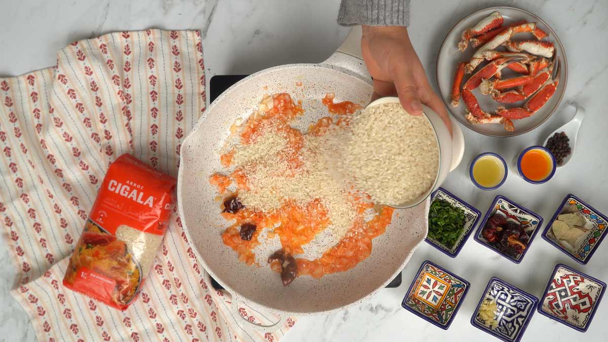 نضيف أرز سيكالا المتوسط إلى المقلاة ليَتشبّع بخليط الطماطم والبصل.